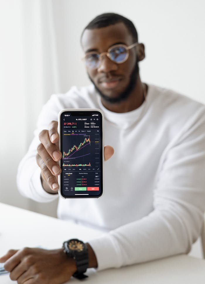 Businessman showing stock graph on smartphone, symbolizing market trends.